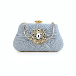 Detail of pleated silver evening clutch with crystal flower brooch and gold shell clasp