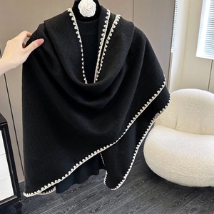 Detailed close-up of a black knitted shawl with elegant white decorative lace trim detail