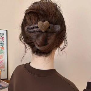 Detailed view of a brown plush heart hair clip used in an elegant braided updo hairstyle