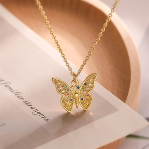 Close-up of golden butterfly pendant necklace with colorful zircons on wooden decor