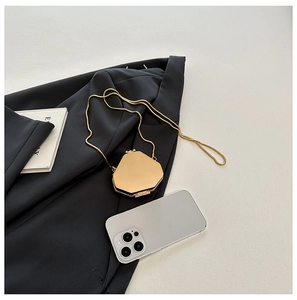 Detailed view of a gold geometric acrylic clutch bag with a delicate metal chain strap