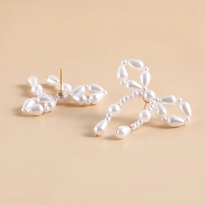 Detailed close-up of handmade white pearl bow earrings with gold-tone studs