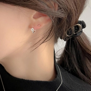 Close-up of 925 sterling silver zircon hoop earrings and stud on model's ear