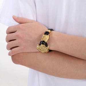 Close-up of golden Mjolnir pendant with wolf head carving on black leather bracelet