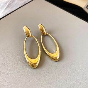 Macro detail of minimalist gold hollow oval drop earrings with polished metallic finish