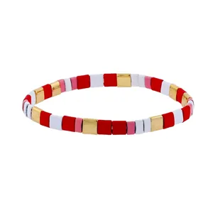 Detail view of handmade bohemian elastic Tila bead bracelet with red, white and gold tiles