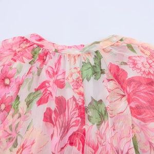 Close-up of ruffled neckline on pink floral chiffon blouse with vibrant flower print