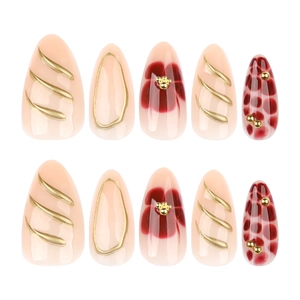 Short almond press-on nails in nude with 3D gold accents and red floral patterns