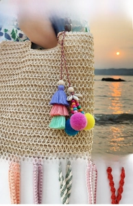 Detail of bohemian bag with colorful tassels, pompoms, seashells and woven straps