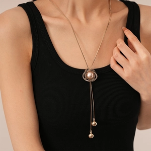 Sautoir vintage fleur de perles dorées avec pompons en strass sur fond de haut noir