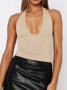 Detail of beige halter bodysuit with gold polka dots paired with black faux leather skirt