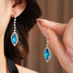 Detailed view of silver long drop earrings with marquise-cut blue gemstone and rhinestones
