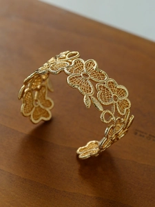 Close-up of 18k gold plated cuff bangle with intricate floral filigree pattern