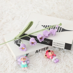 Macro shot of handmade purple crochet lily of the valley flowers on a vintage book
