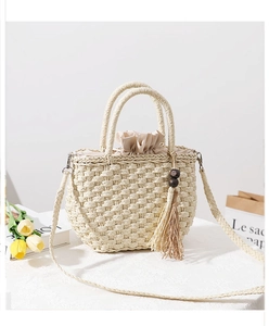 Detail of straw handbag with drawstring lining, fringe tassel and wooden bead accents