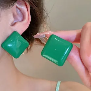 Gros plan de boucles d'oreilles carrées vert vif avec finition brillante sur un mannequin