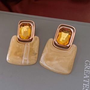 Detailed macro shot of vintage geometric resin earrings with amber crystal and gold alloy