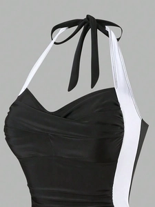 Detail of black and white color block swimsuit with halter neck and pleated bust design
