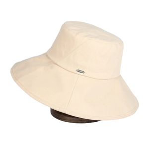 Beige wide brim cotton canvas sun hat with metal logo plate on white background