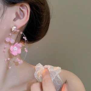 Macro detail of pink fabric flower earring with sparkling rhinestones on model