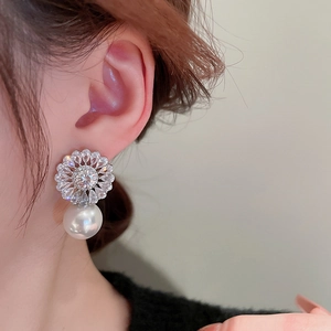 Close-up of model wearing floral zircon silver earrings with large white pearl drops