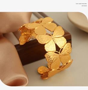 Macro detail of 18K gold-plated butterfly cuff bracelet with intricate brushed texture
