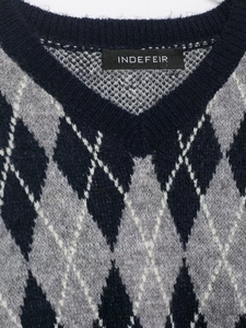 Detailed close-up of V-neckline and argyle knit pattern on navy blue sweater