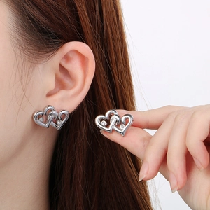 Macro detail of silver interlocking heart earrings with cubic zirconia on a model