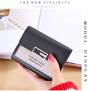 Detail of a bicolor three-fold leather wallet with litchi texture and metal buckle