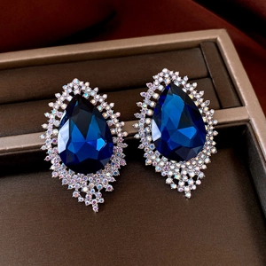 Detail of dark blue teardrop earrings with halo rhinestones on velvet background