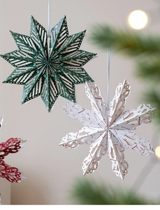 Close-up of hanging 3D paper snowflakes and stars with festive Christmas pine background