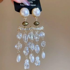 Detail of luxury pearl and crystal tassel earrings with green beads and gold finish