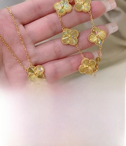 Macro detail of gold-plated clover jewelry featuring radial texture and titanium steel material
