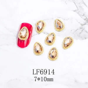 Detalle de gemas para uñas en forma de gota con borde de metal dorado y piedras champán