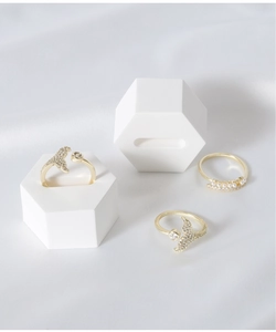 Detailed macro view of gold dolphin tail rings with pearls on white hexagon display