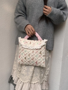 Detail showing floral quilted laptop bag with soft pink handles and white lace trim