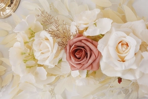 Detail of cream and dusty rose artificial flowers with golden leaves for wedding decor