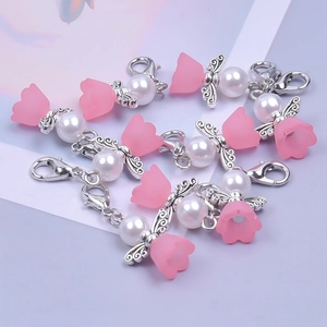 Detail of pink flower bell charm with white pearl, silver wings and lobster clasp