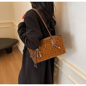Gros plan d'un sac cabas léopard avec anses marrons porté sur un manteau d'hiver noir