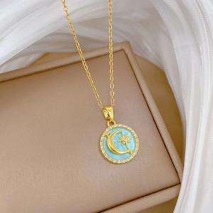 Detail of gold necklace with star moon pendant in light blue enamel and crystal halo