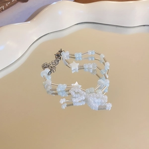 Detail of beaded double-layer bracelet with white stars and blue beads on a mirror