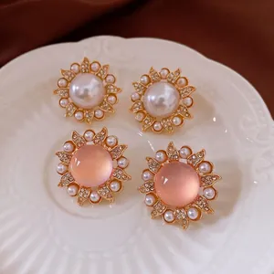Boucles d'oreilles fleur en perle et pierre rose sur plat en céramique blanc en relief