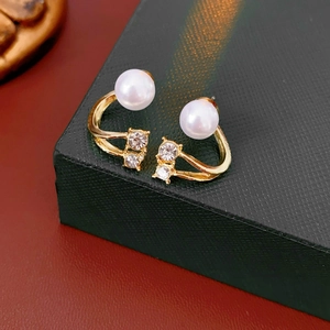 Gros plan de boucles d'oreilles perles dorées avec diamants sur écrin noir texturé