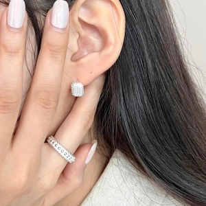 Close-up of minimalist silver rectangular stud earrings and zirconia ring on model