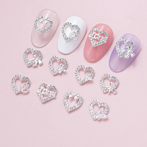 Macro shot of silver alloy heart nail charms with rhinestones and bow details