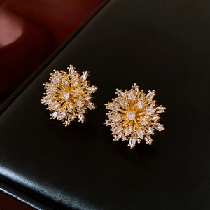 Macro shot of gold floral stud earrings featuring sparkling marquise-cut crystals on leather
