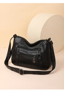 Detail of black crossbody bag with triple zippers and lychee texture leather finish