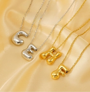 Macro shot of 3D bubble letter pendants in gold and silver finish on satin fabric