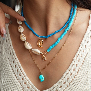 Detail of layered bohemian necklace with blue beads and golden turtle shell pendants