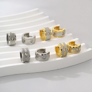Dettaglio di orecchini in acciaio 18k oro e argento spazzolato con diamanti incastonati